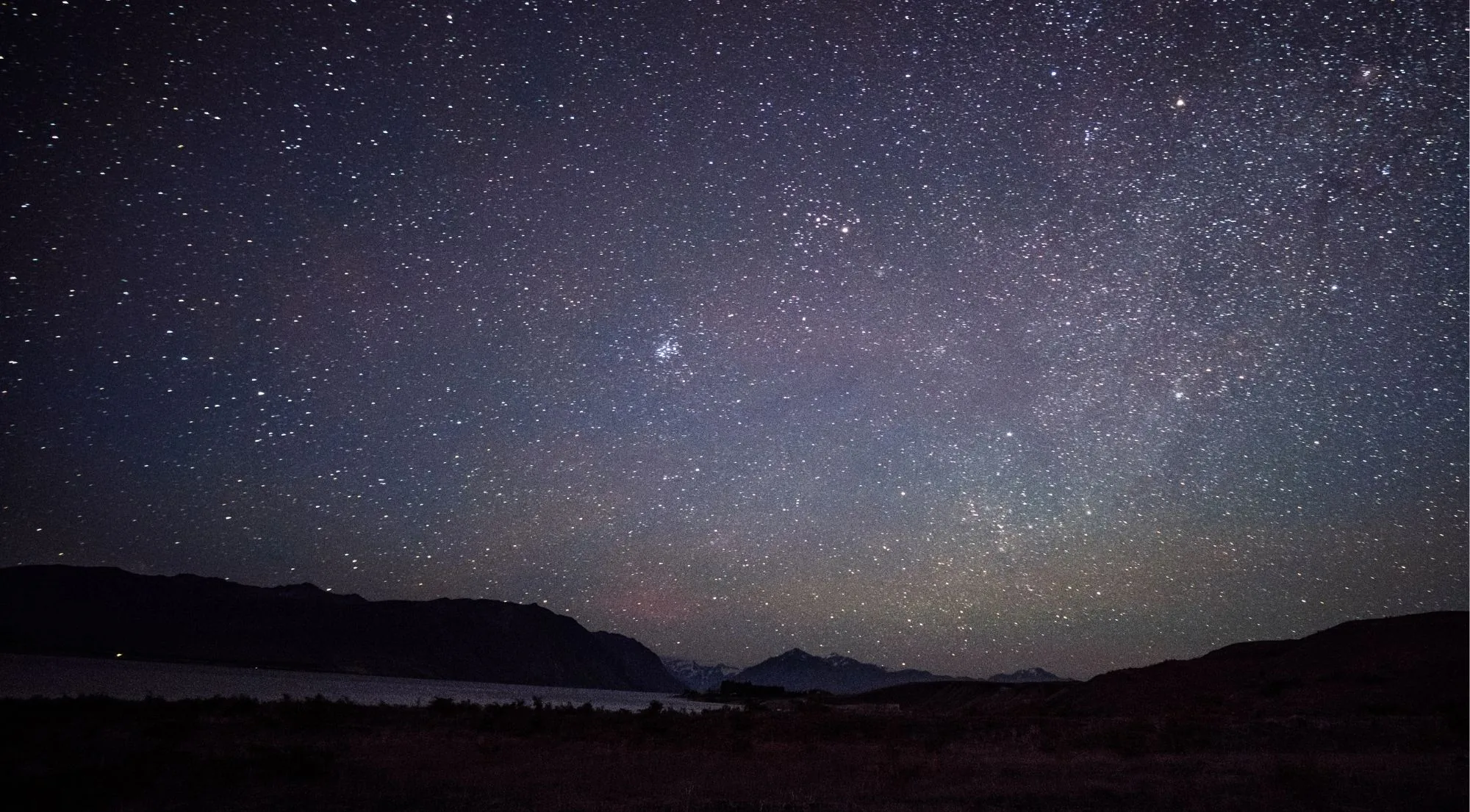 Starry night sky over Lake Tekapo and the surrounding mountains