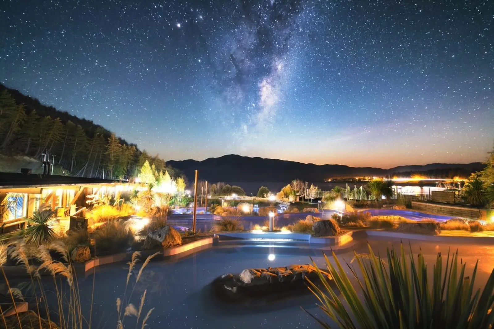 Tekapo Springs hot pools complex lit at twilight under the Milky Way