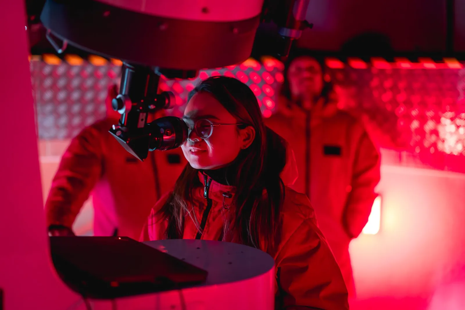 Guest looking through an eyepiece under red light inside a Mount John dome