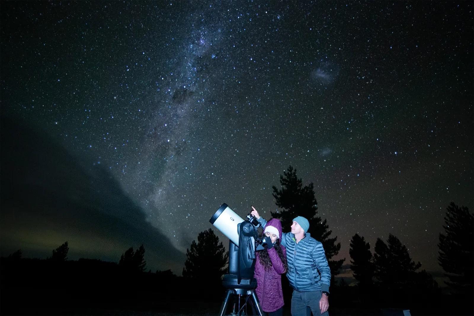 Chameleon Stargazing guests gathered around the telescope under a starry sky