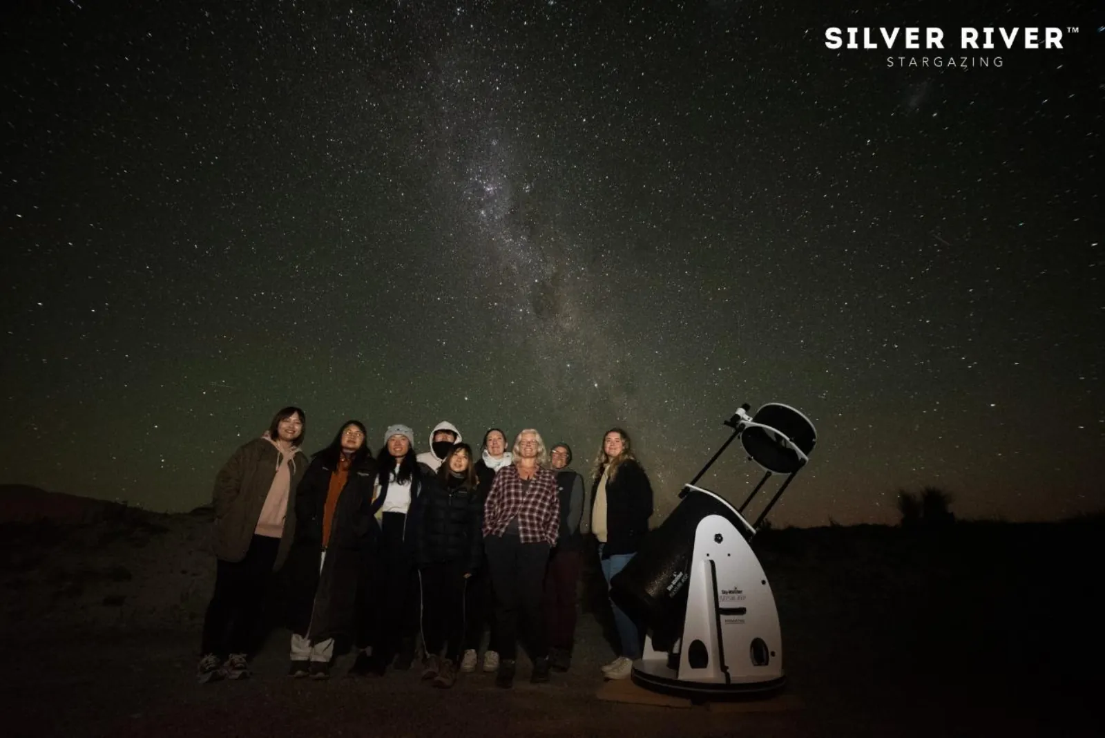 Silver River Stargazing group standing beside a telescope at night