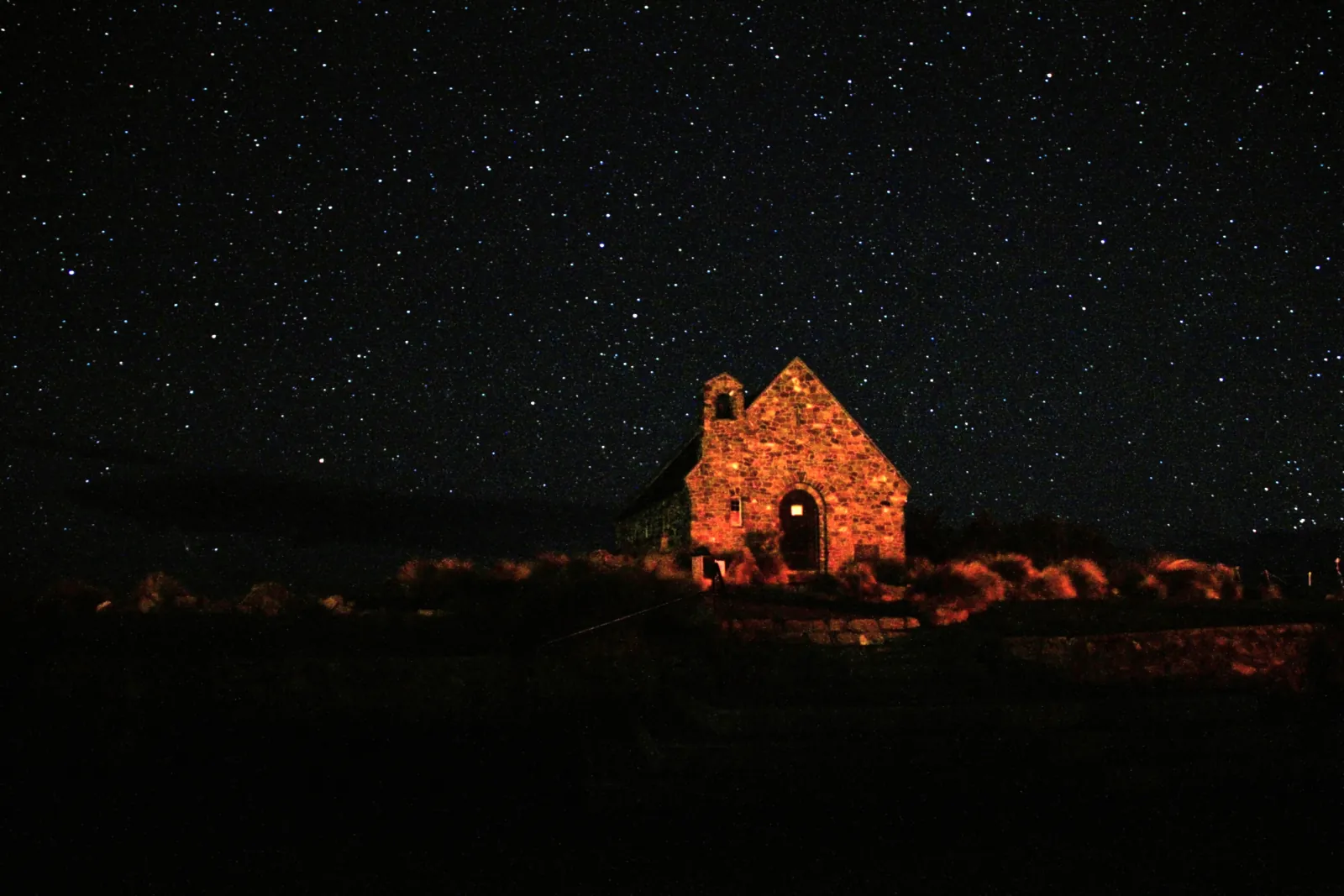 Church of the Good Shepherd lit at night under the stars at Lake Tekapo